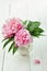 Pink peonies in retro vase on wooden table