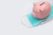 Pink pig piggy bank on a non-sterile green mask and a mercury medical thermometer