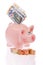 Pink piggy bank with coins and bills