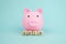 Pink piggy bank with geometric wood blocks cube adt text SALE on blue background. Saving money for sales of the year, black friday