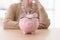 Pink piggy bank with glasses stands on wooden table at lady