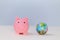 Pink piggy bank and globe, copy space. Savings money for travelling concept. Rosy moneybox, thrift-box and earth symbol