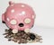 Pink piggy bank on its side with coins and bills falling out of opening