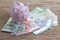 Pink piggy bank on pile of Euro banknotes on wooden table, financial savings money account or Europe economics concept, future gr