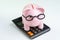 Pink piggy bank wearing glasses on black calculator on white background using as budget, cost or investment calculation and