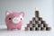pink piggy money bank with coins pyramid, step up growing business to success and saving for retirement concept