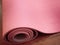 Pink pilates, yoga or fitness mat on wooden floor.