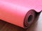 Pink pilates, yoga or fitness mat on wooden floor.