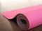 Pink pilates, yoga or fitness mat on wooden floor.