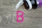 Pink pills forming shape to B alphabet on wood background