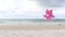 Pink pinwheel toy spinning on white sand beach, colorful wind turbine windmill on the beach with summer sea and blue sky as back