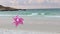 Pink  pinwheels toy spinning on white sand beach, two colorful wind turbines windmill on the beach in the morning with s