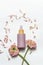 Pink pipette cosmetic bottle with empty label mock up on white background with flowers and petals. Skin care with facial serum.