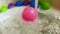 Pink plastic ball rolled by water stream in bath tub, slow motion
