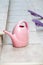 Pink plastic watering can stands on  step