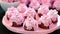 A pink plate topped with cupcakes covered in frosting, spring petit four cakes. Spring petit four cakes.