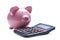 Pink porcelain piggy bank near a desk calculator