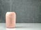 A pink portable air humidifier on a white table on a gray background