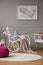 Pink pouf and flowers in grey baby`s bedroom interior with poster and rocking chair. Real photo