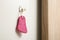 Pink pumice stone hanging on white wall, space for text