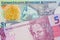 A pink and purple five real bank note from Brazil paired with a colorful one dollar note from the Cayman Islands.