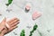 Pink quarts face roller, gua sha stone, pink cream in glass jar. Off white flat lay in green, pink colors with ice and