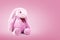 Pink rabbit doll with big ears on sweet background. Cute stuffed animal and fluffy fur for kids