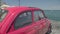 Pink retro car parked on pier in resort town, travel and vacation, summer time