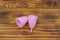 Pink reusable silicone menstrual cups on wooden background. Top view. Concept of feminine hygiene, gynecology and health