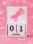 Pink ribbon of breast cancer awareness on a white wooden perpetual calendar with date 01 october. International breast cancer