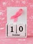 Pink ribbon of breast cancer awareness on a white wooden perpetual calendar with date 10 october. International breast cancer