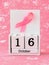 Pink ribbon of breast cancer awareness on a white wooden perpetual calendar with date 16 october. International breast cancer