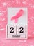 Pink ribbon of breast cancer awareness on a white wooden perpetual calendar with date 22 october. International breast cancer