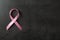 Pink ribbon and space for text on dark background, top view. Breast cancer awareness