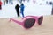 Pink-rimmed sunglasses on wooden slope in apres ski bar or cafe, with ski slope in background. Concept of winter sports, leisure,