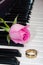 Pink rose and golden ring on the piano keyboard