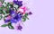 Pink rose, lilac irises and purple Aquilegia flowers on a light pink background. Spring bouquet in pastel colors. Delicate cold sh