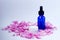 Pink rose petals, blue bottle and white cream composition, light background, horizontal view.