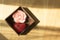 Pink rose and red heart scented aroma candle in wooden box on wooden background with light and shadow from window .spa concept