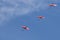 Pink roseate spoonbills fly in a formation line.