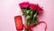 Pink roses bouquet with hart shaped bow and mobile phone with copy space screen