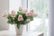 Pink roses in vase on background window