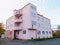 Pink round corner house building at intersection of streets. Blue sky