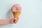Pink round macrame yarn skein in ice cream cone in woman hand. Creative macrame knitting idea