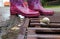 Pink rubber boots on a drainage grid with snail in rainy weather