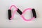 Pink rubber tube expander with black paralon handles for performing fitness exercises with hands in the form of an infinity sign
