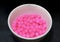 Pink sago with syrup in the circle bowl on the black floor.