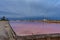 Pink salt pool at sunrise with dark clouds, ultra long exposure