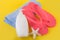 Pink sandal flip flop on blue towel and suntan cream lotion and starfish on yellow background