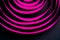 The pink satin ribbon is arranged in spiraling circles on a black background. Abstract background